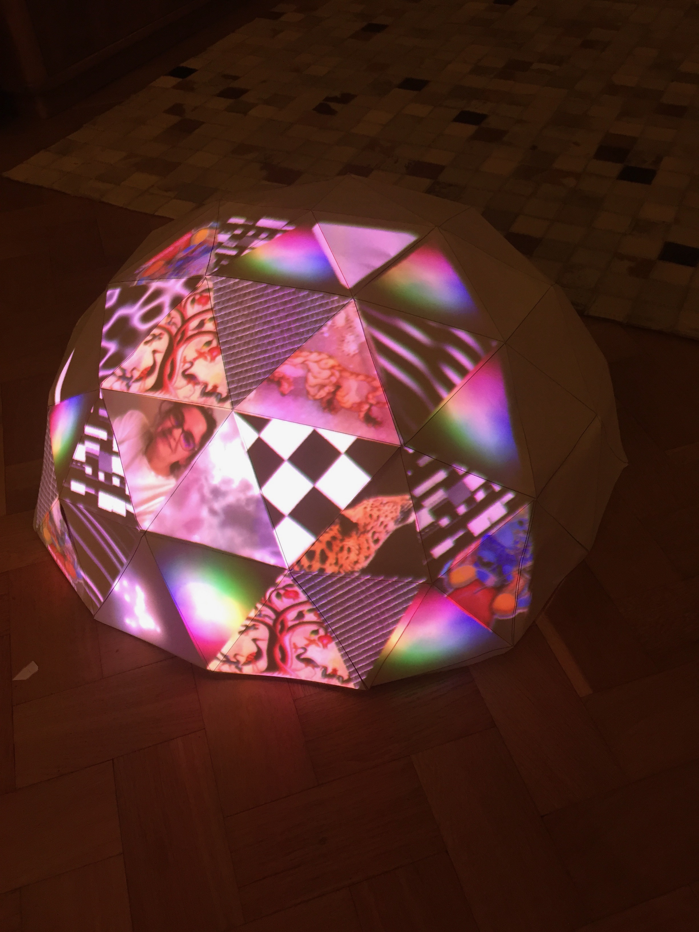 A geodesic dome in paper, with various pictures mapped and projected on its faces.